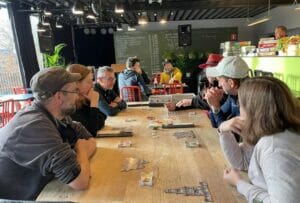 hommes et femmes autour d'une table en train de jouer à un jeu de société